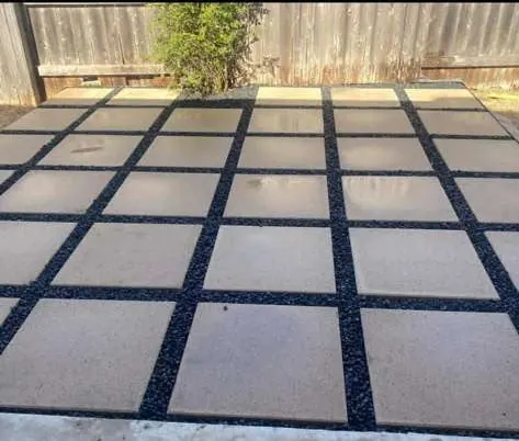 Large concrete patio pads separated by black gravel joints